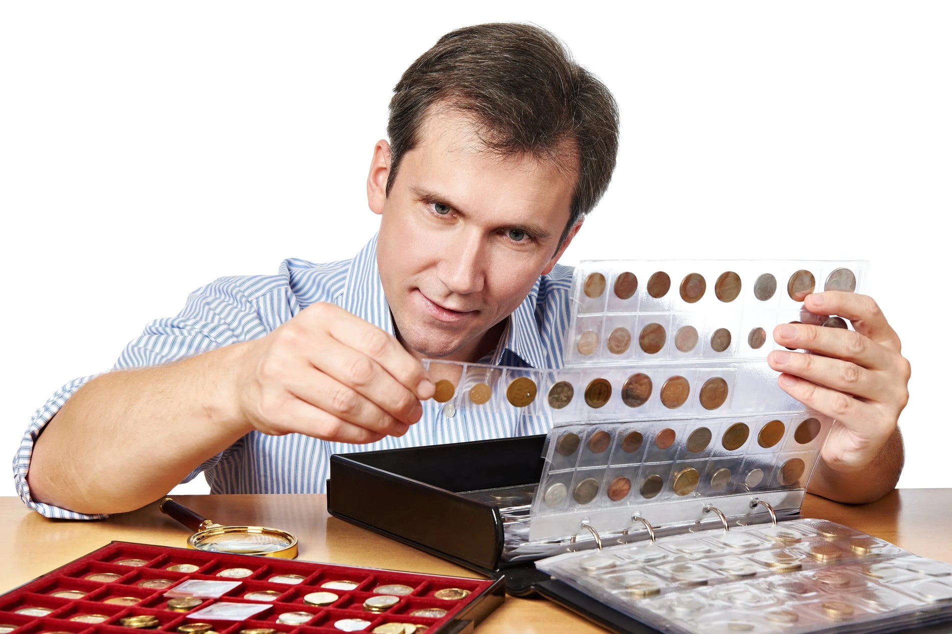 Man examining coins from a collector's binder, with jewelry displayed nearby.
